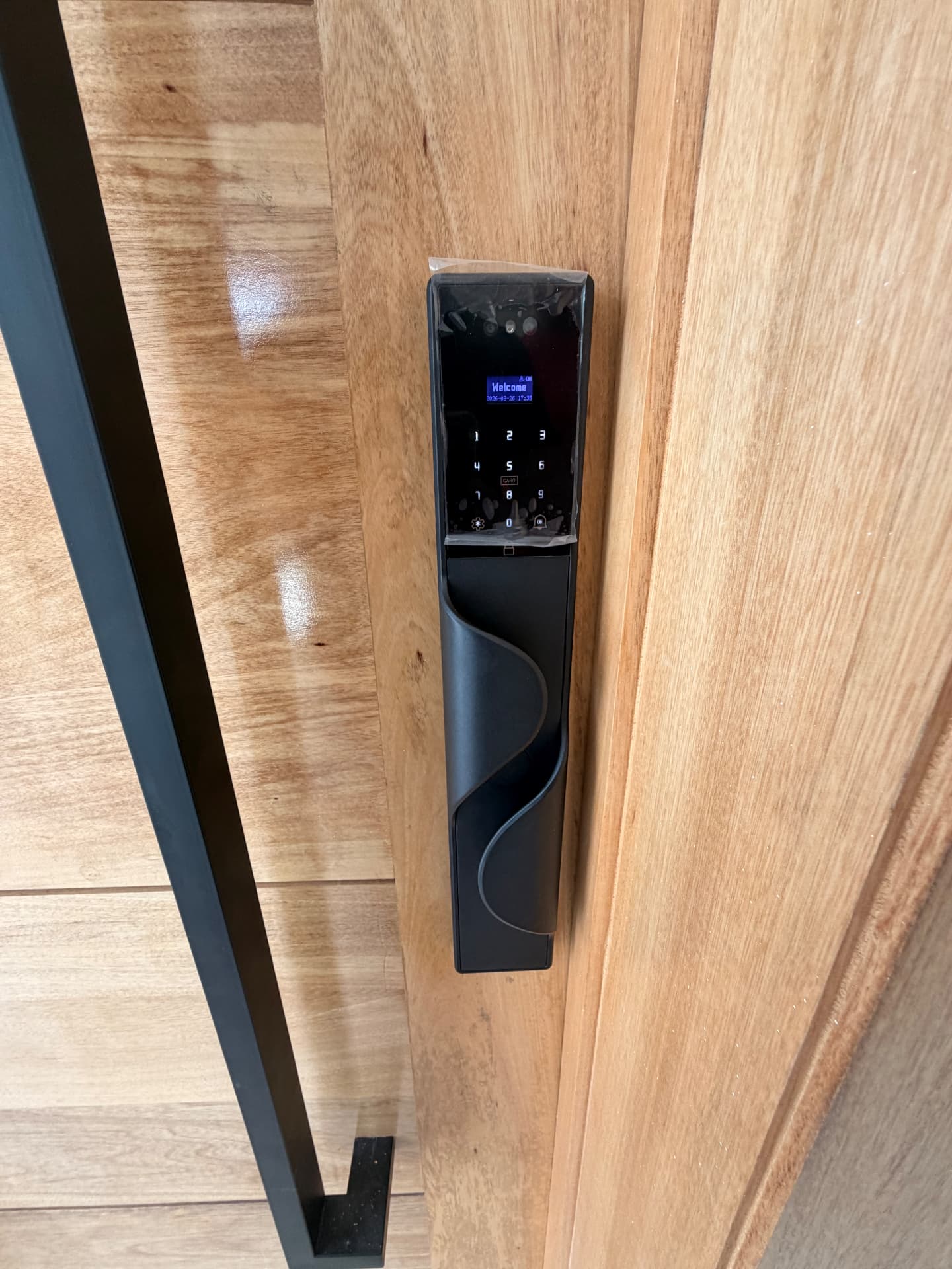 Cerradura inteligente con teclado y huella instalada en puerta de madera